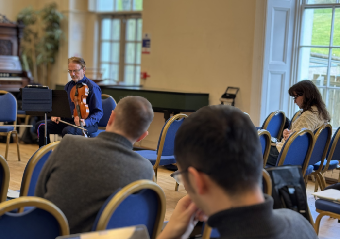 picture of composers in a room with musicians performing